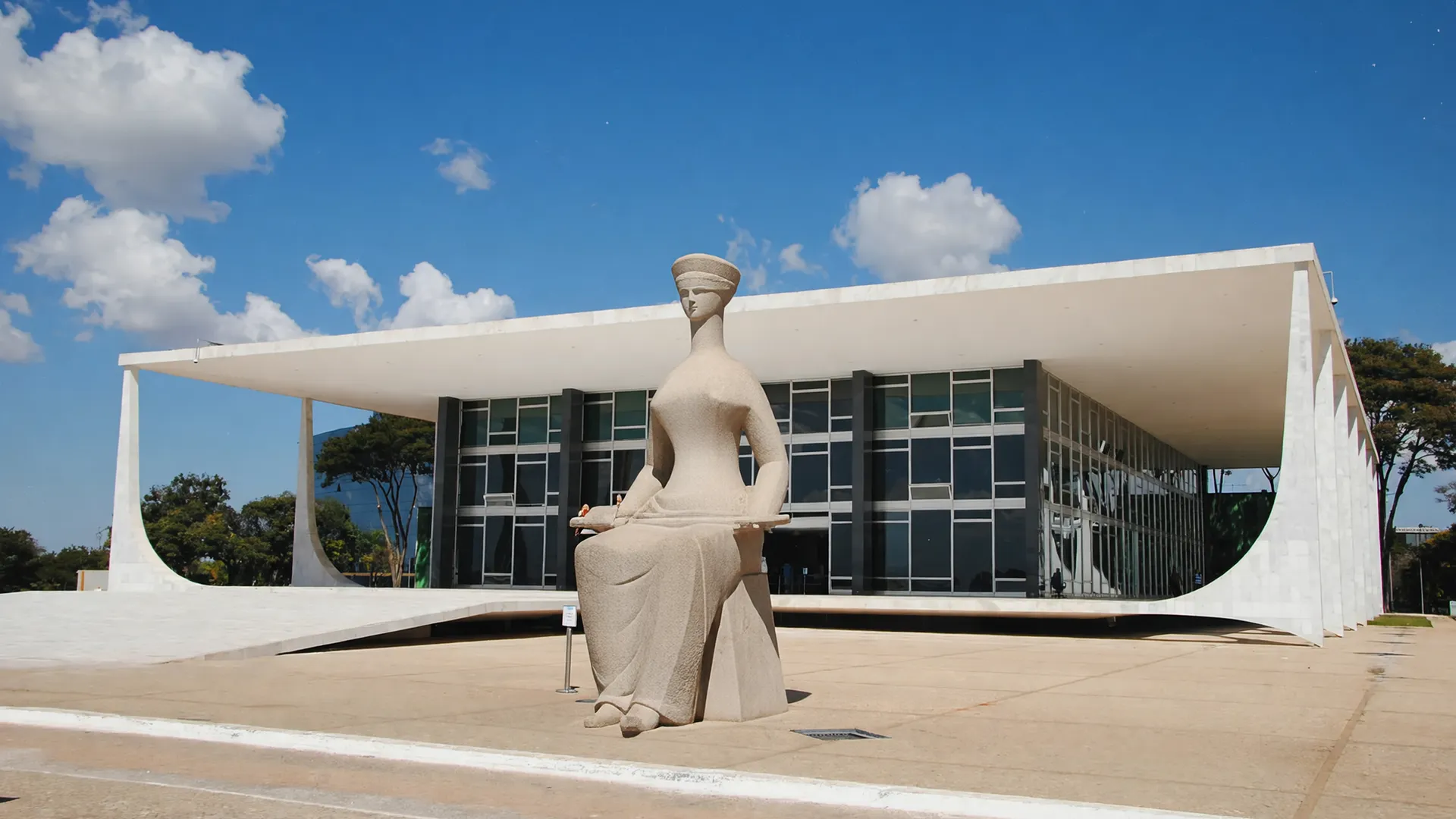 STF com escultura da justiça em primeiro plano, representando decisão institucional sobre desincompatibilização de candidatos