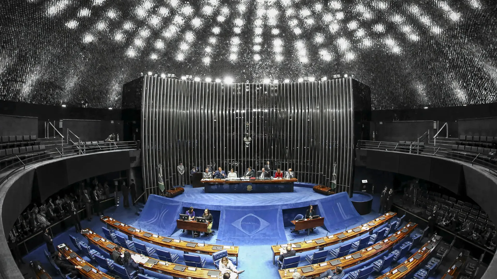 Plenário do Senado Federal com cadeiras azuis em semicírculo, mesa presidencial e câmeras, simbolizando aprovação de reajuste salarial