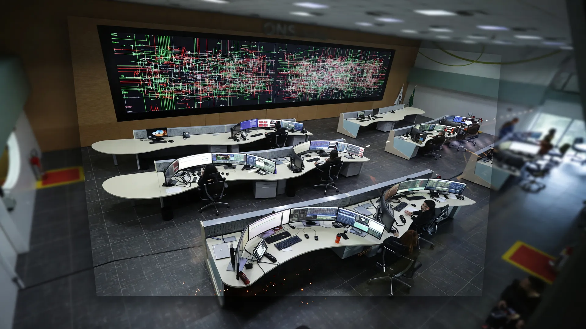 Centro de operações em alerta com monitores mostrando plano emergencial excedente energia distribuída