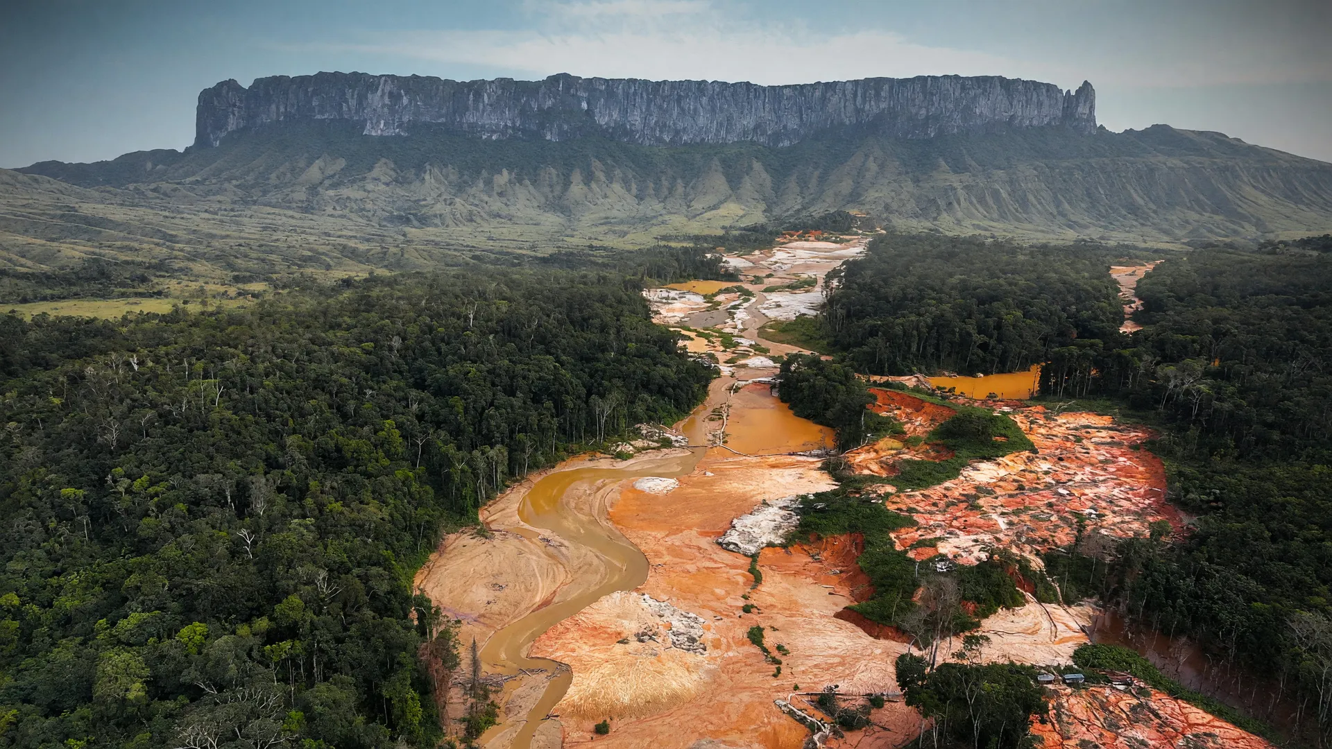 Vista aérea de garimpo ilegal na Amazônia, com o Monte Roraima ao fundo, ilustra alta na apreensão de ouro ilegal no Norte