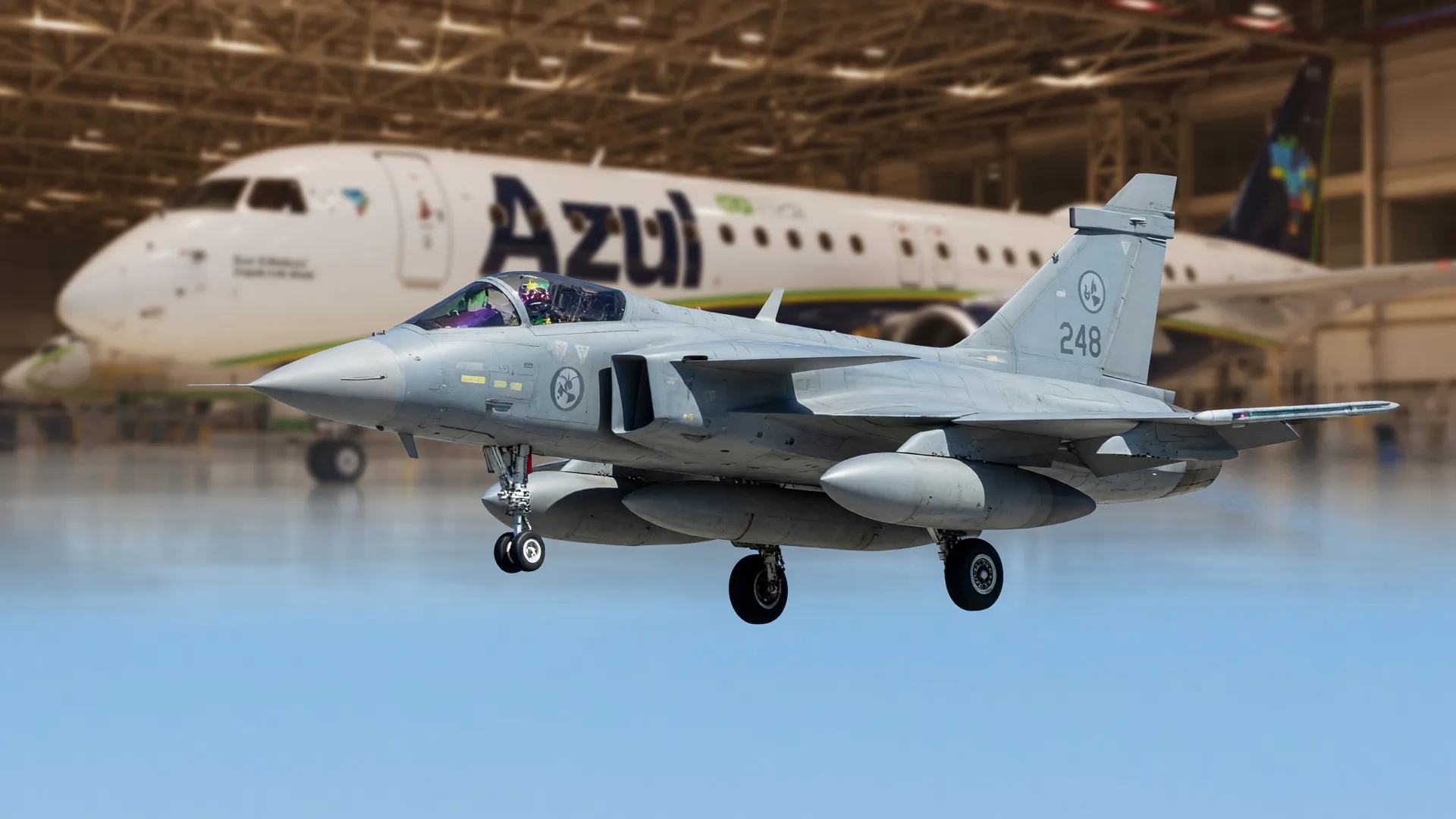 Caça Gripen em voo com hangar da Embraer ao fundo, remetendo à produção de caças Gripen em Gavião Peixoto