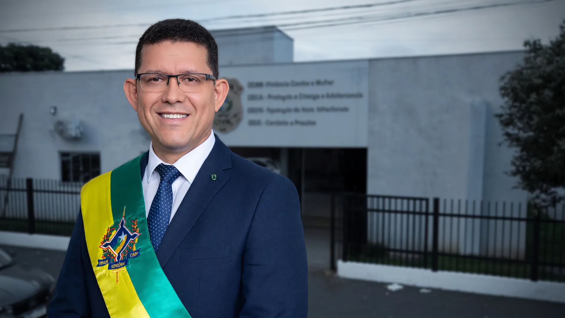 Governador Marcos Rocha ao lado da fachada da delegacia da mulher Rondônia, símbolo de promessa não cumprida