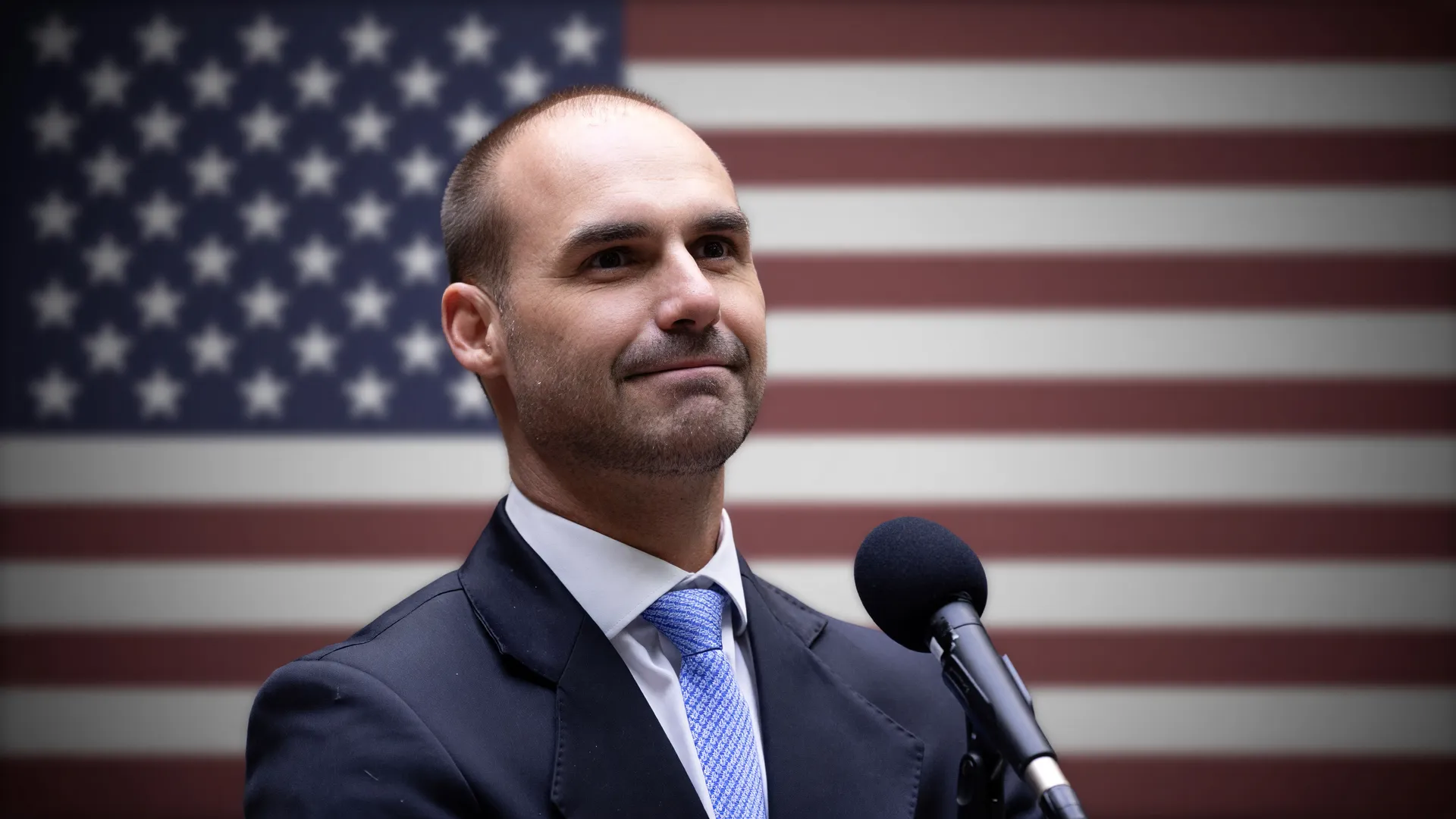 Eduardo Bolsonaro com bandeira dos EUA ao fundo, ilustrando a demissão de Eduardo Bolsonaro da PF