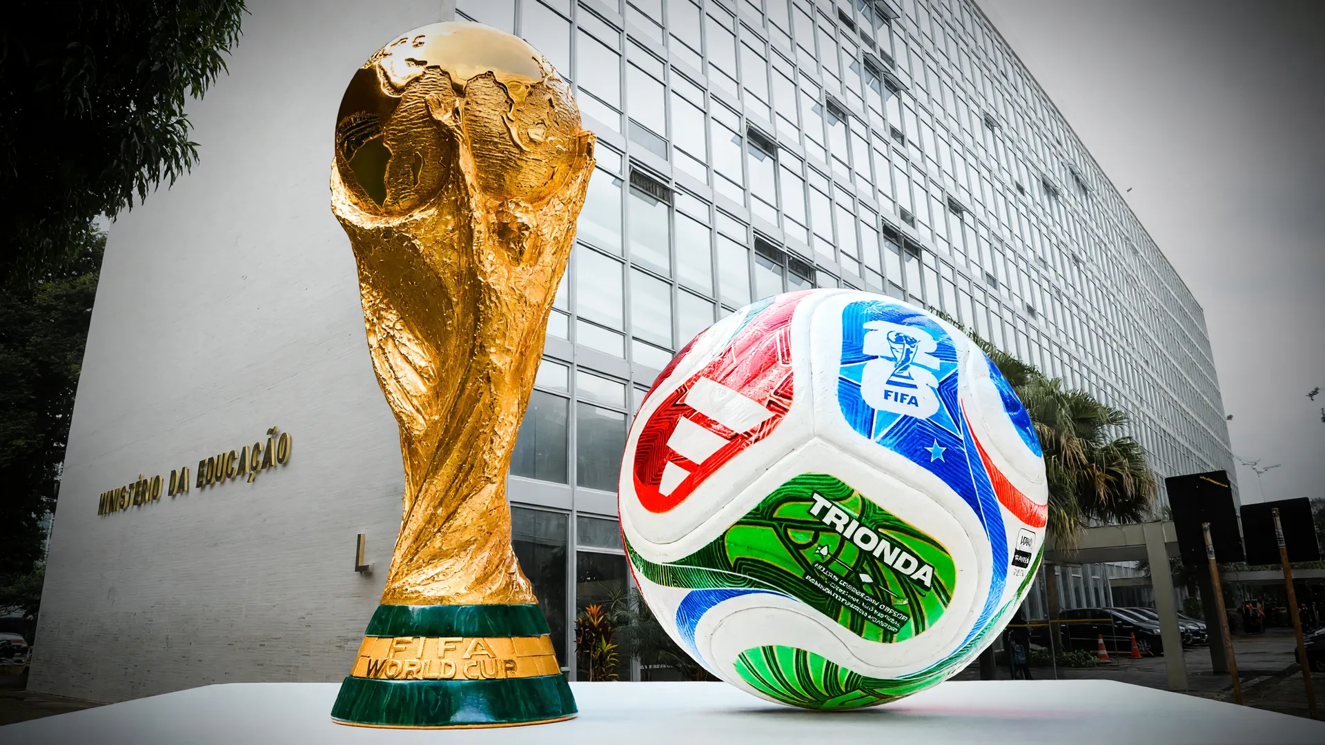Taça FIFA e edifício do MEC em colagem editorial sobre férias escolares Copa Feminina 2027