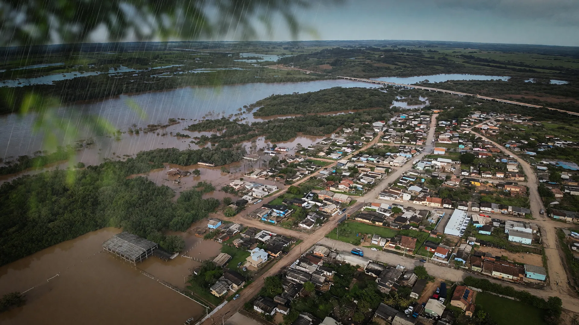 Vista aérea mostra área urbana submersa durante inundações no Rio Grande do Sul, com casas e ruas alagadas.