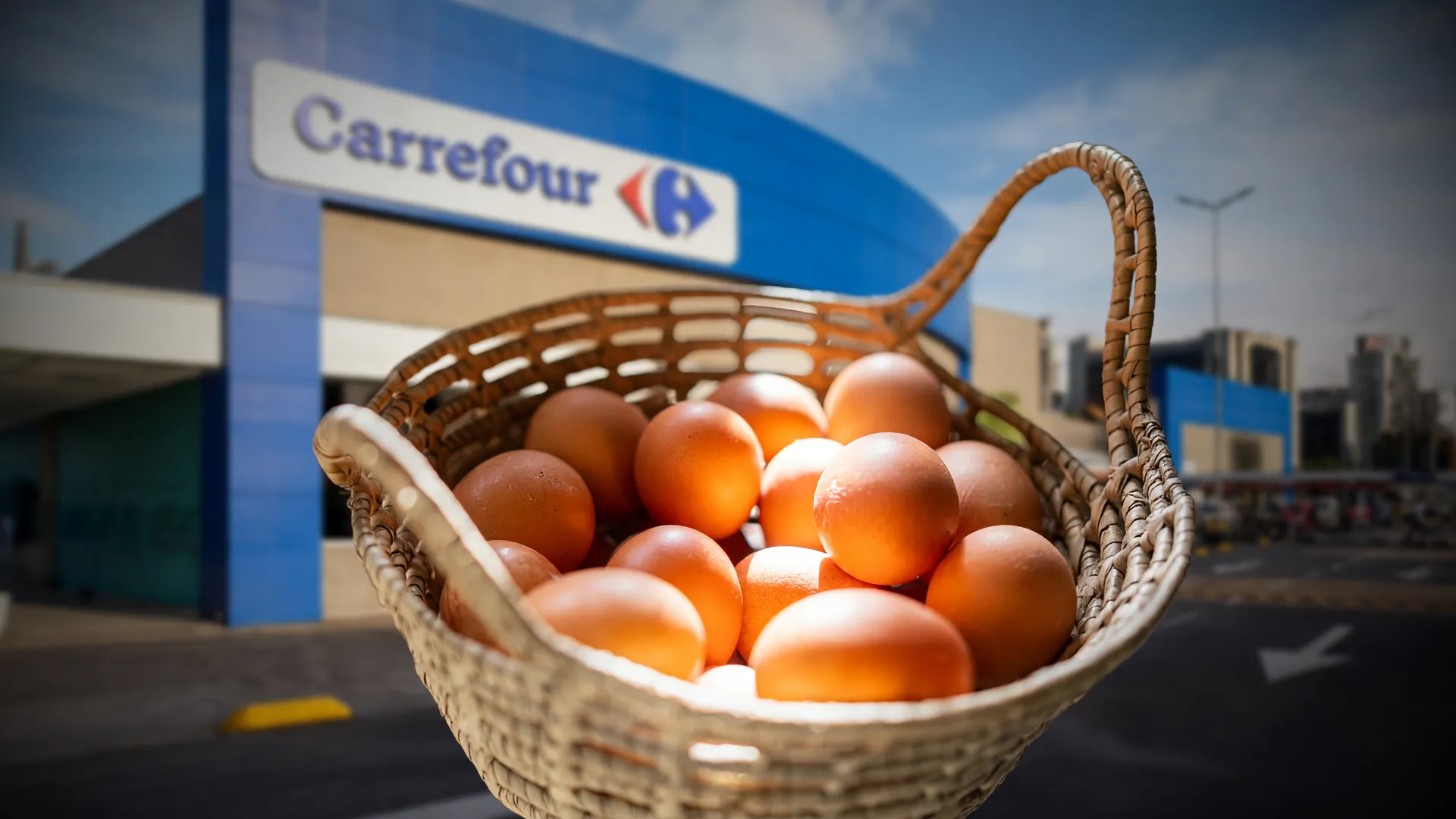 Ovos livres de gaiolas supermercados: cesto de ovos marrons em destaque com fachada do Carrefour ao fundo