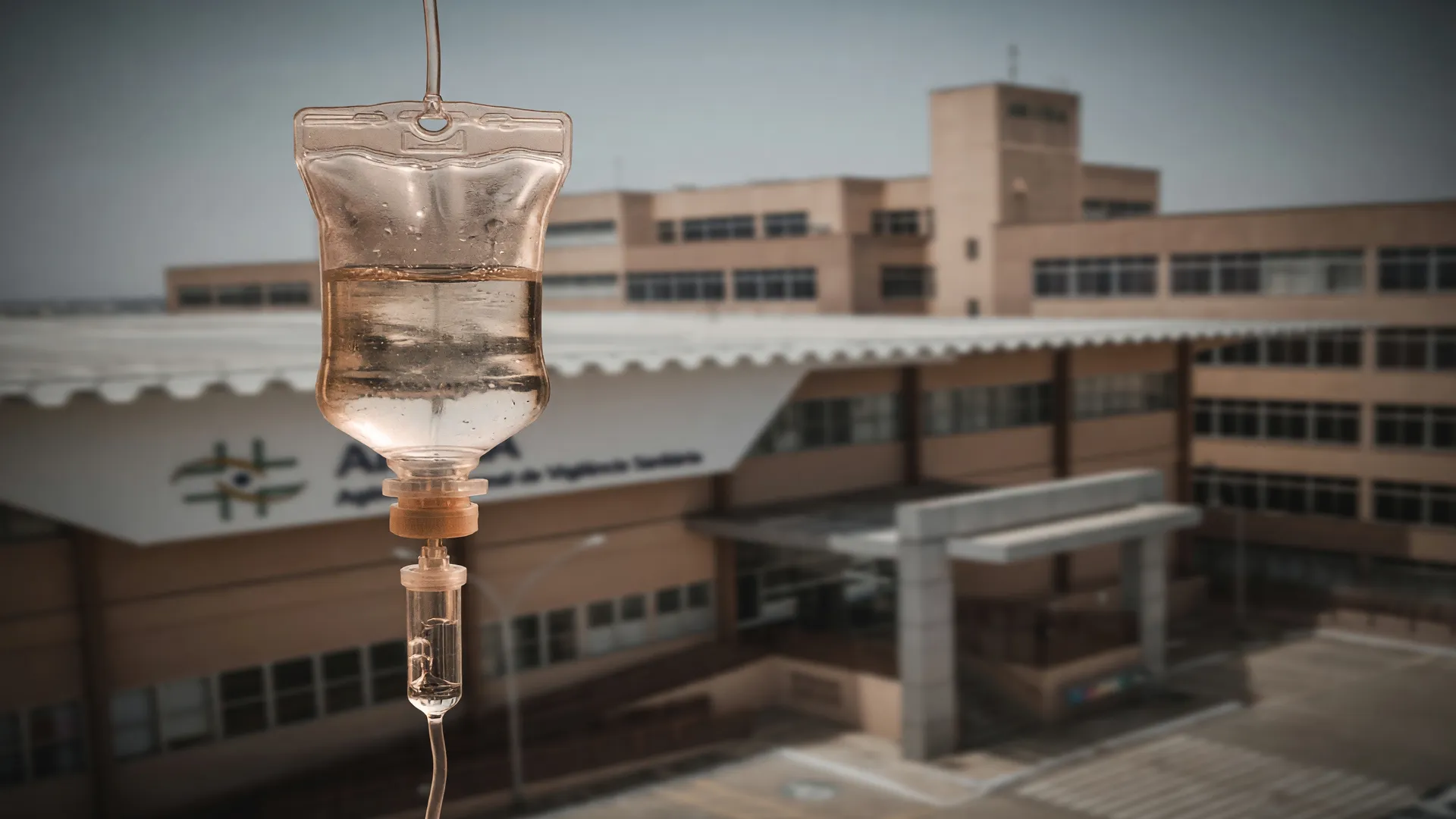 Bolsa de soro intravenoso com sede da Anvisa ao fundo, alertando sobre riscos da soroterapia intravenosa.