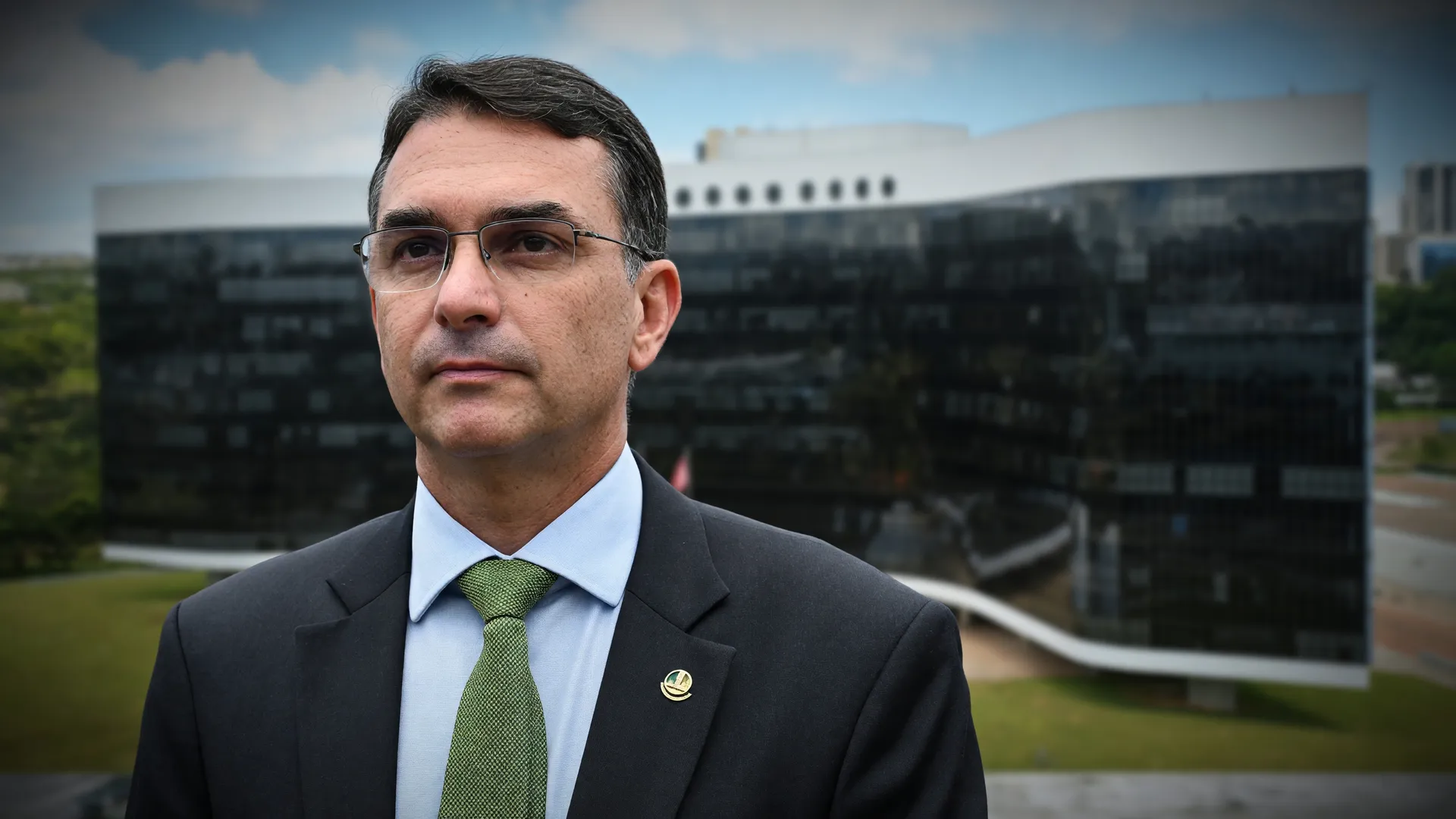 Flávio Bolsonaro em retrato formal; ao fundo, sede do TSE, no contexto da declaração de bens Flávio Bolsonaro
