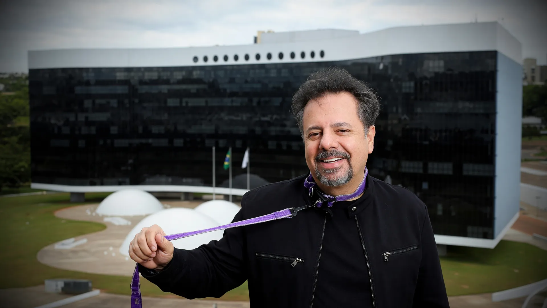 Wilson Grassi sorri com credencial, ao fundo fachada do TSE — declaração de bens Wilson Grassi chega a R$ 50 milhões