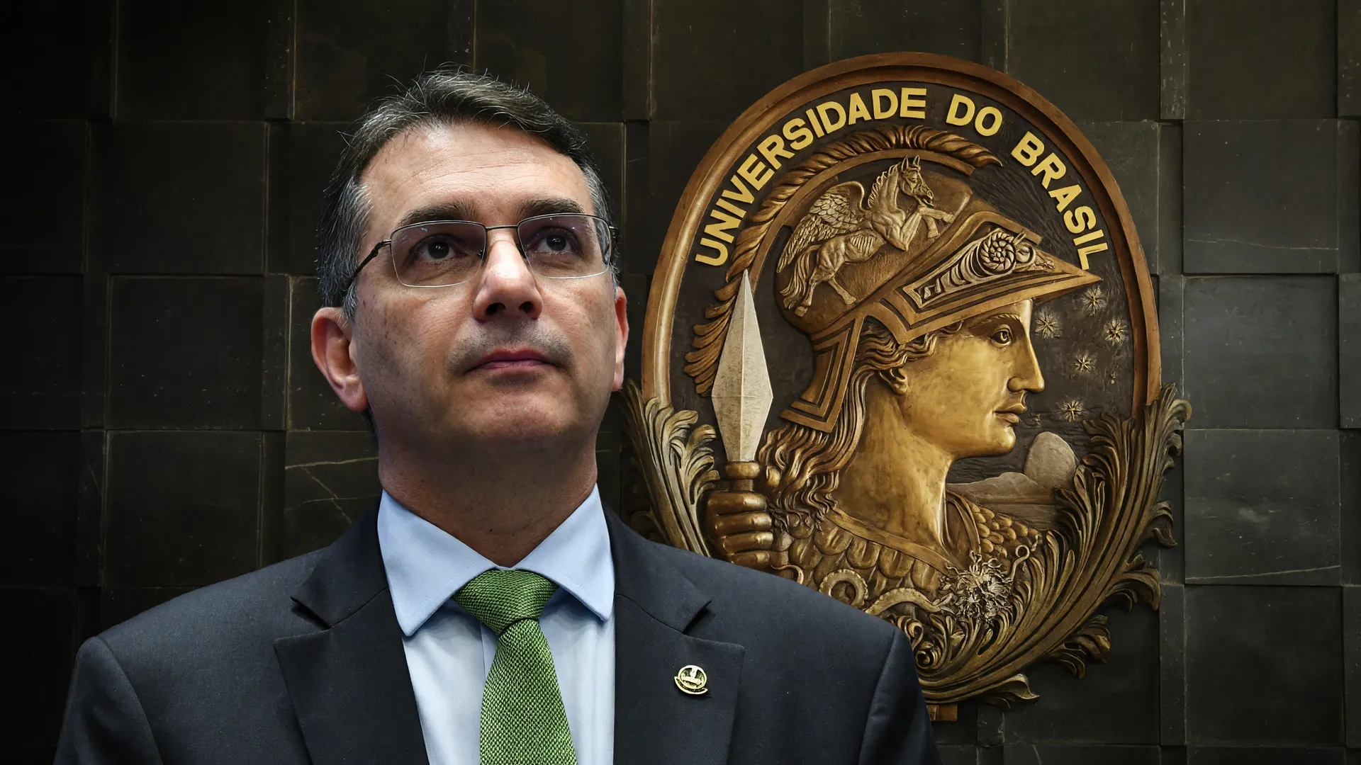 Flávio Bolsonaro em retrato institucional com símbolo da UFRJ ao fundo, no centro da polêmica sobre pós-graduação UFRJ