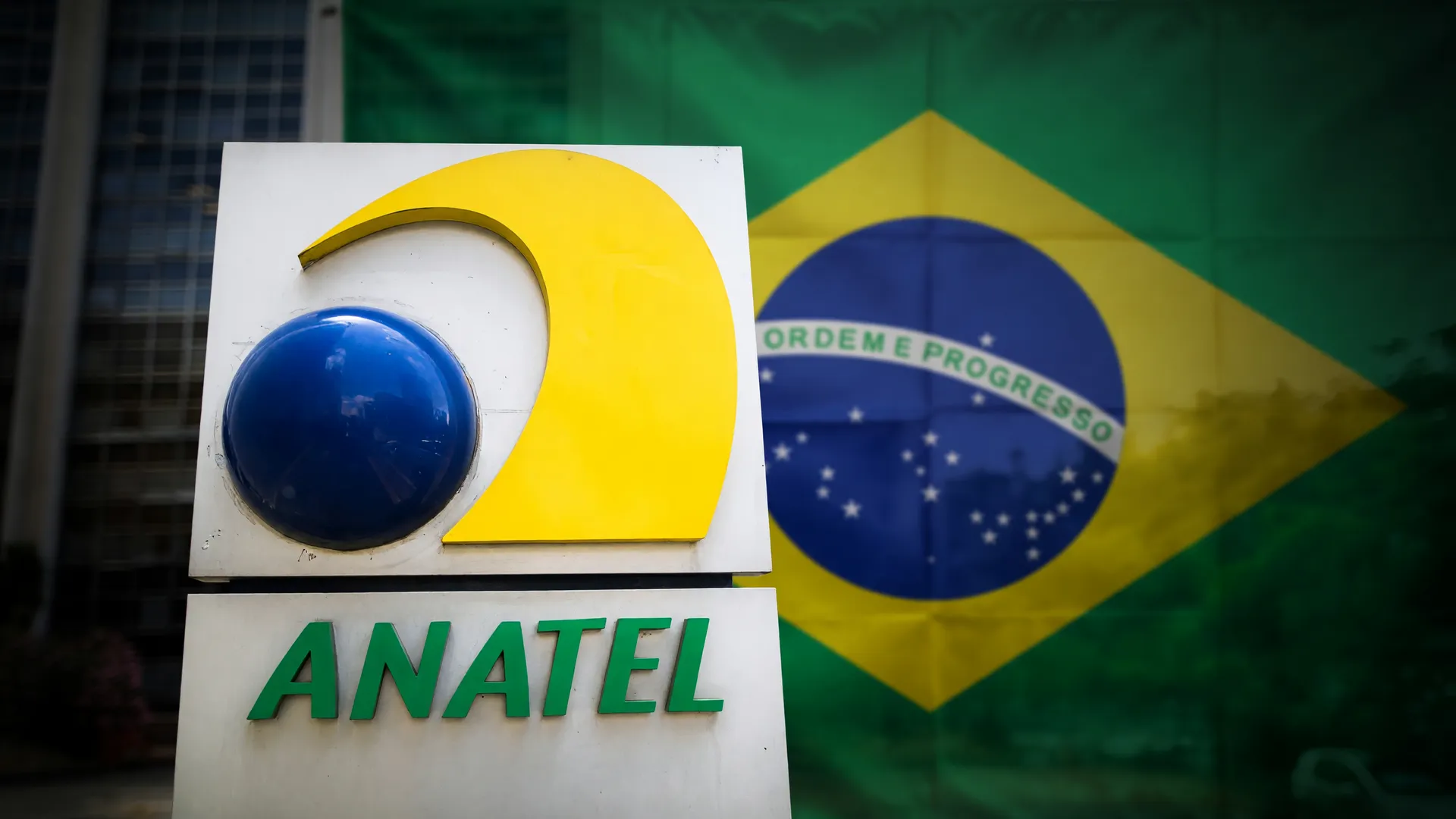 Placa institucional da Anatel com bandeira do Brasil ao fundo, simbolizando fiscalização contra o golpe da antena falsa