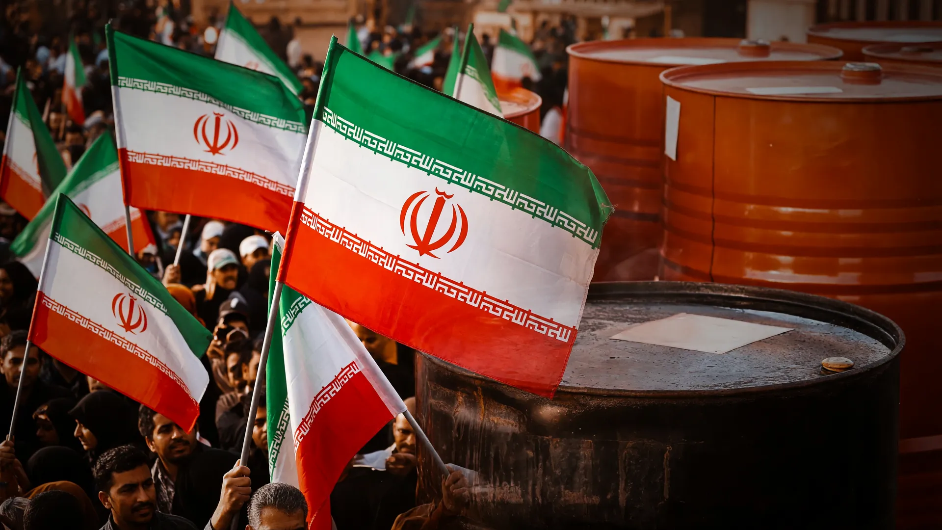 Multidão iraniana com bandeiras e barris de petróleo ilustram impacto da guerra no Irã seis meses após início do conflito