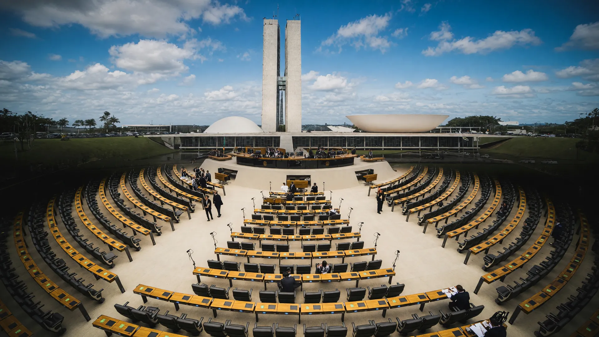 Plenário da Câmara dos Deputados em debate sobre multas de câmeras com IA, com Senado ao fundo como próxima etapa