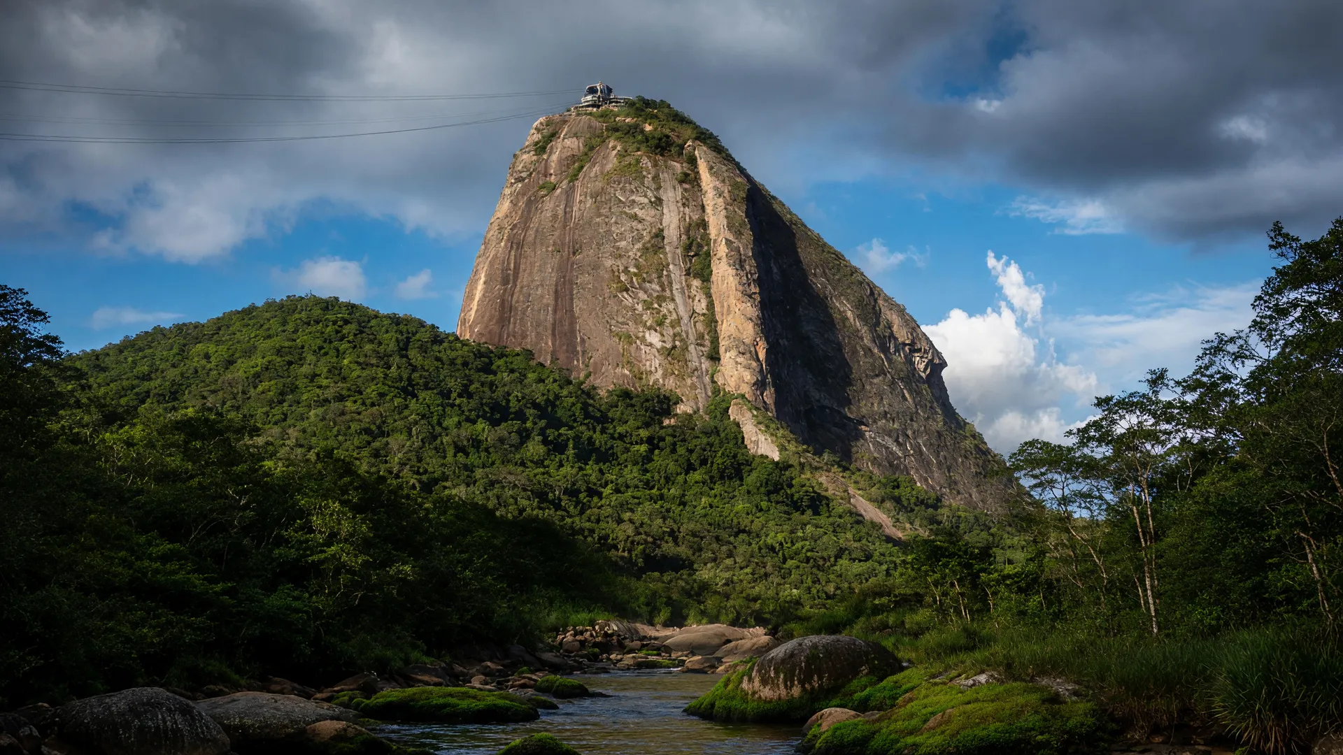 obras tirolesa Pão de Açúcar suspensas: vista do morro icônico com Mata Atlântica preservada e céu dramático
