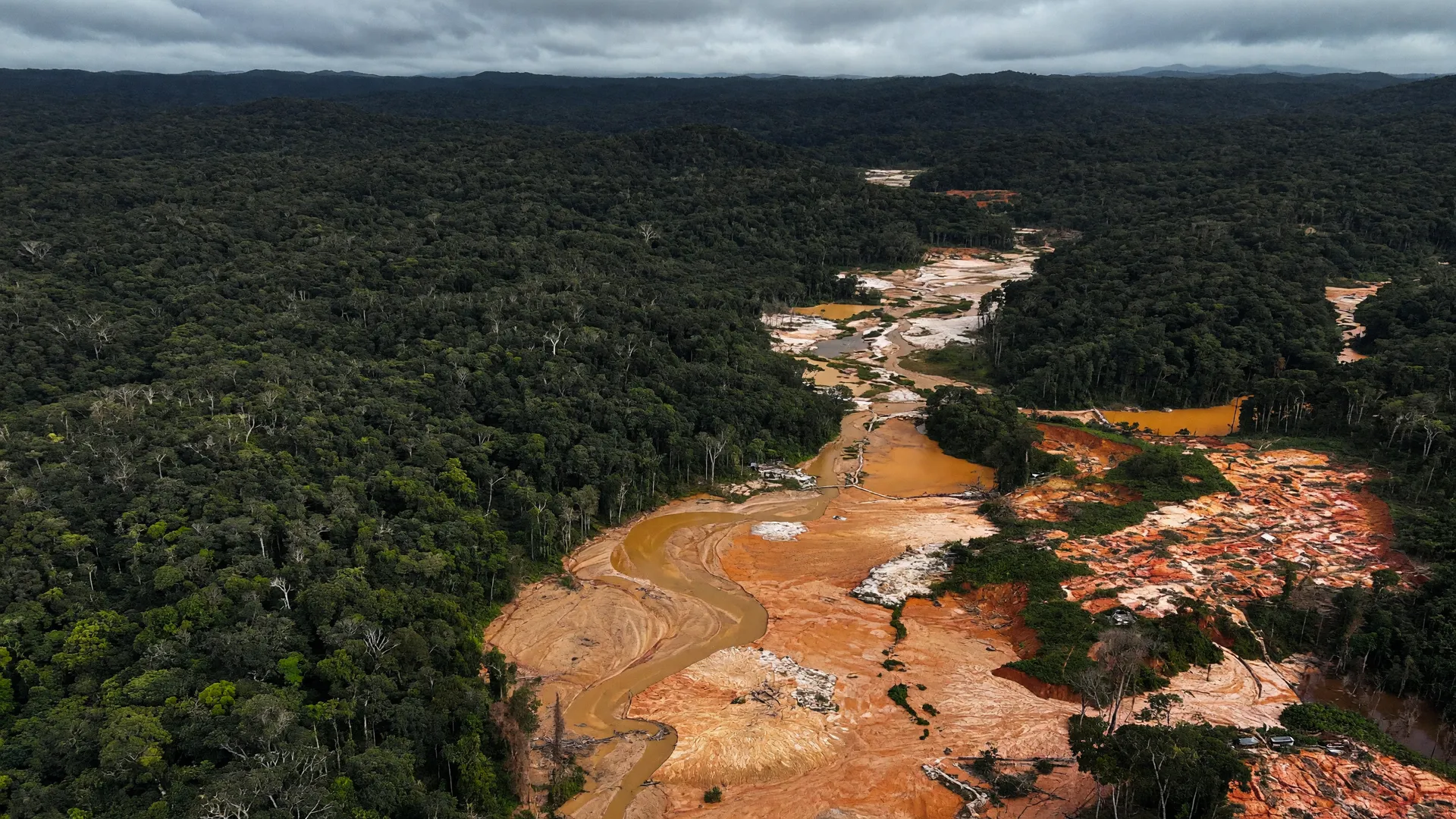 Vista aérea do garimpo no rio Madeira mostra água alaranjada cortando a floresta amazônica degradada