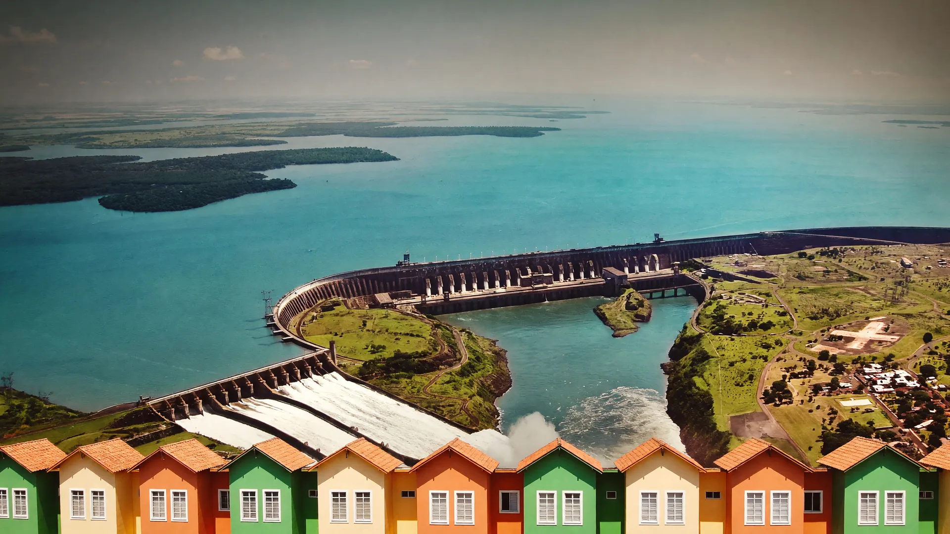 Vista aérea de Itaipu e habitações coloridas do MCMV ilustram IPCA deflação agosto 2026 com queda na conta de luz