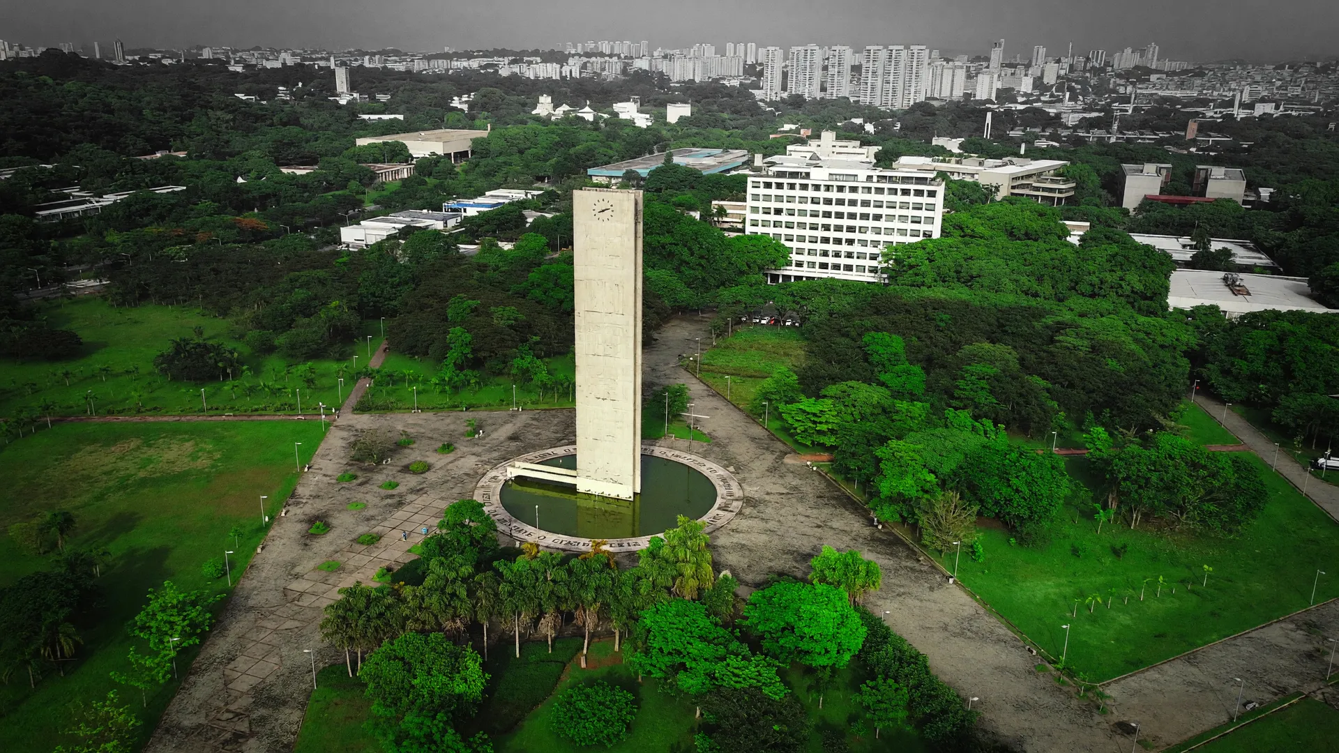 Vista aérea da USP com vegetação exuberante e cidade ao fundo, evocando parques urbanos e regulação climática em São Paulo