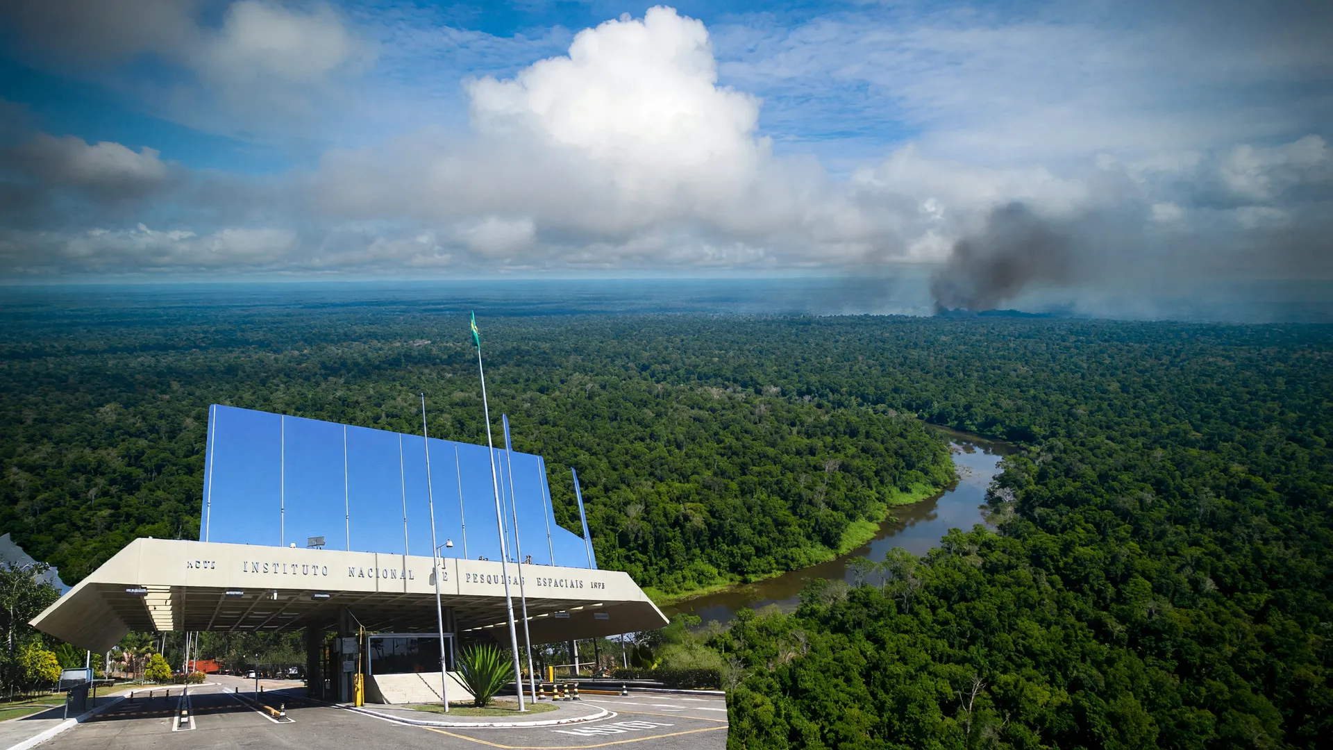Vista aérea da floresta amazônica e a entrada do Inpe, ilustrando estudo sobre as emissões de carbono da Amazônia