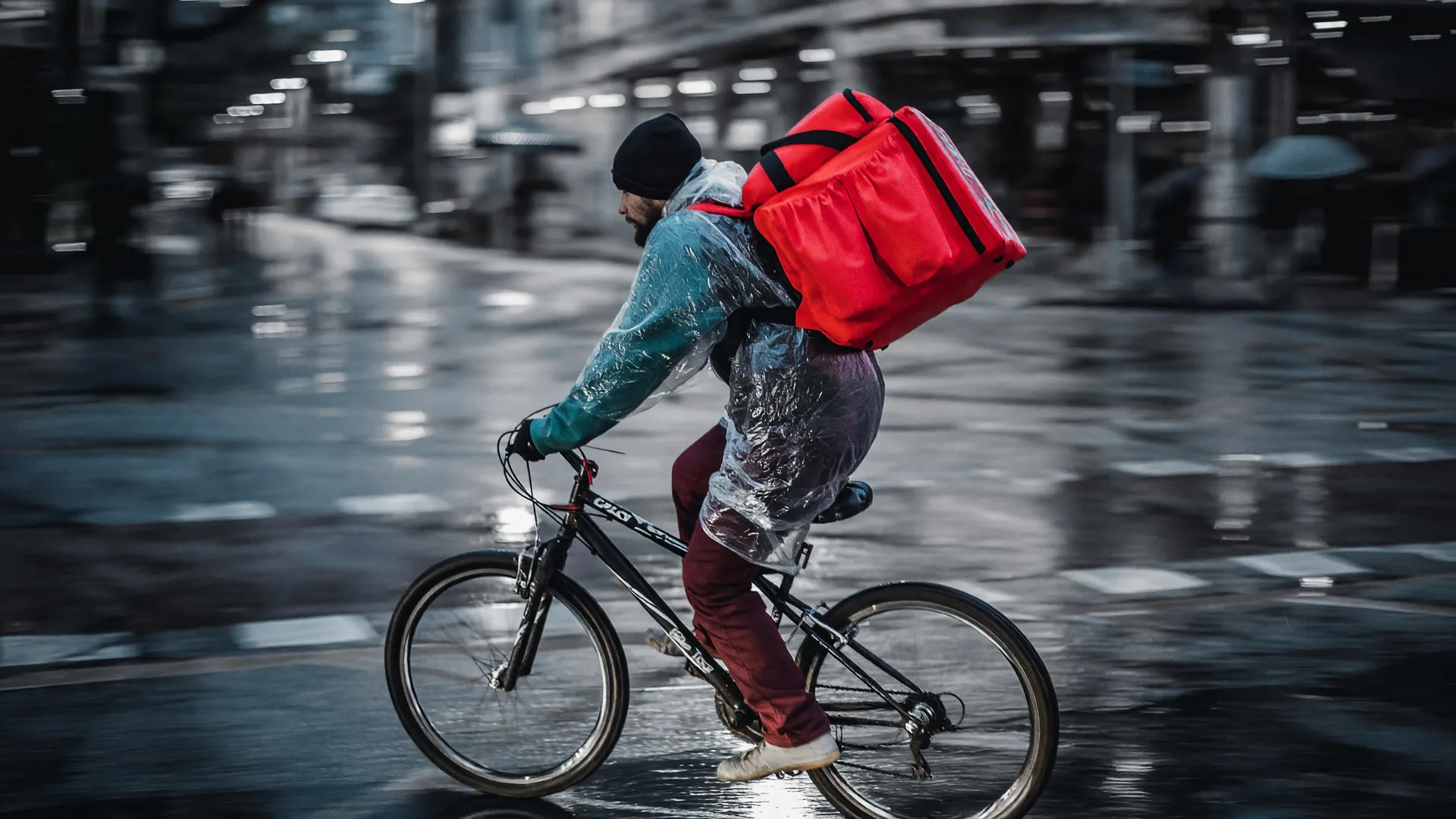 Trabalhador informal enfrenta chuva à noite, símbolo do trabalho precário na fruticultura no Brasil.