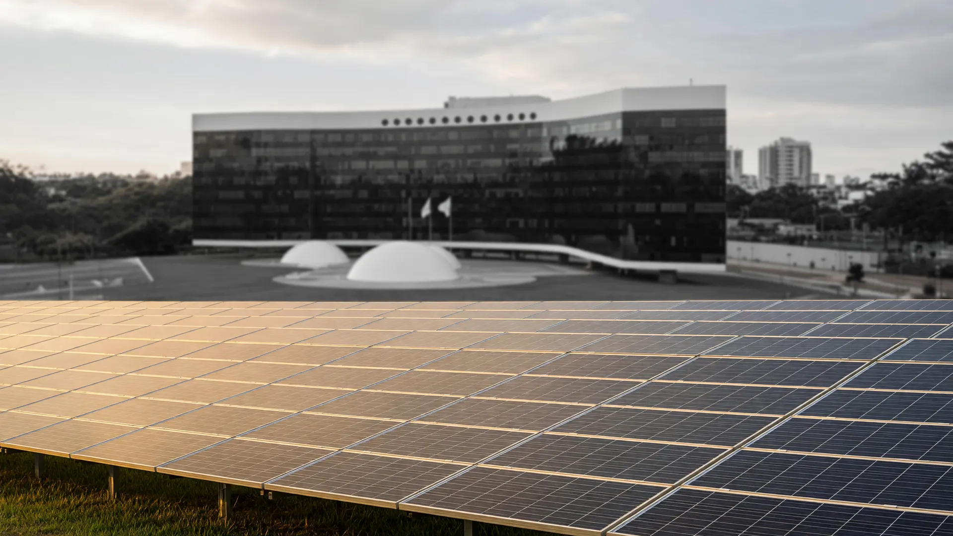 Painéis fotovoltaicos ao entardecer ilustram a usina solar do TSE, com a sede do tribunal ao fundo